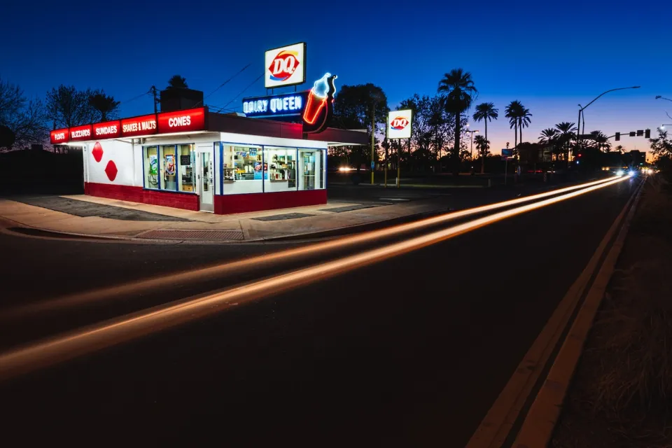 Historic Dairy Queen restaurant building with neon signs at night.